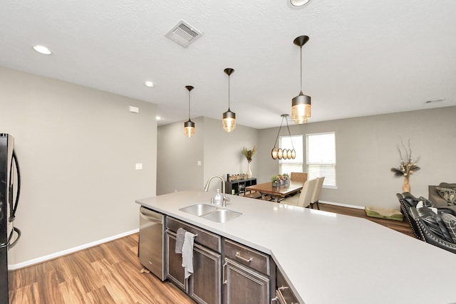 kitchen featuring stainless steel appliances, pendant lighting, light countertops, and a sink