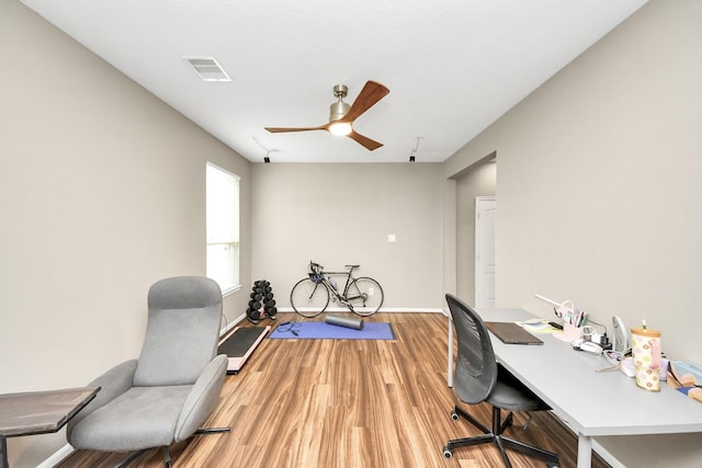 office featuring a ceiling fan, baseboards, visible vents, and wood finished floors