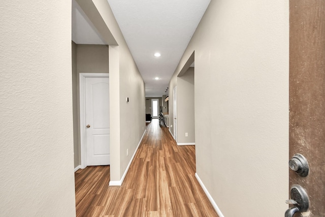 hallway featuring baseboards and wood finished floors