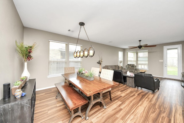 dining room with light wood-style floors, visible vents, baseboards, and ceiling fan with notable chandelier