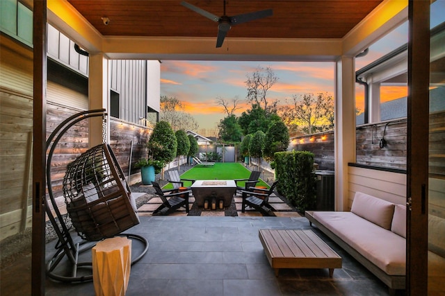 patio terrace at dusk featuring an outdoor hangout area, a yard, a fenced backyard, and a ceiling fan