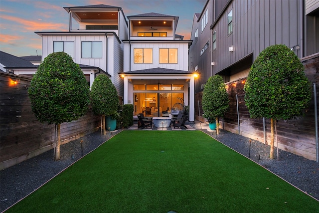 rear view of house with a yard, board and batten siding, a patio area, and a fenced backyard