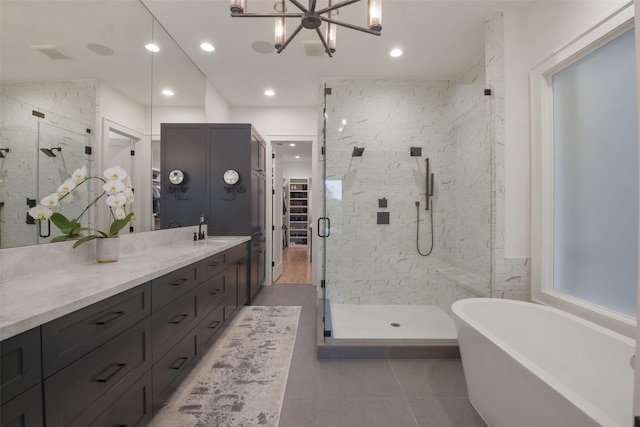 bathroom with tile patterned floors, a spacious closet, a freestanding bath, vanity, and a shower stall