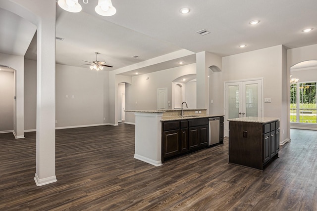 kitchen with arched walkways, a sink, visible vents, dishwasher, and an island with sink