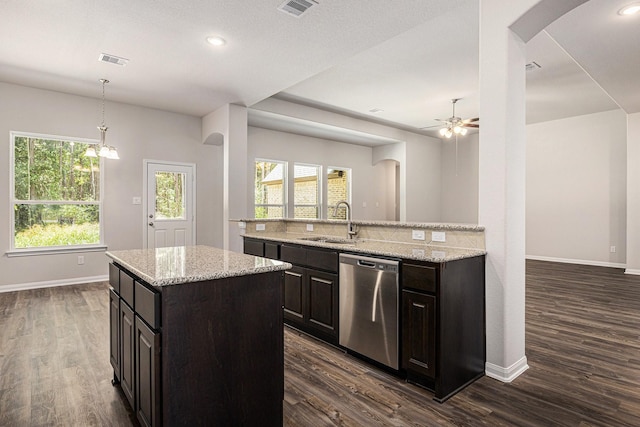 kitchen with arched walkways, pendant lighting, a center island with sink, a sink, and dishwasher