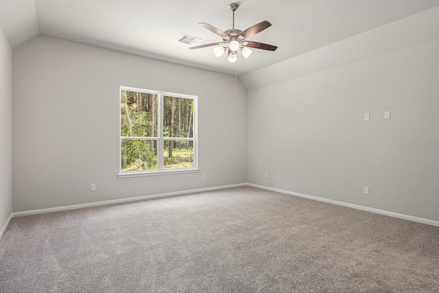 carpeted spare room featuring vaulted ceiling, baseboards, visible vents, and a ceiling fan