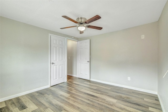 empty room featuring light wood finished floors, baseboards, and a ceiling fan