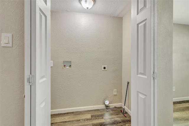clothes washing area with dark wood-style flooring, a textured wall, electric dryer hookup, laundry area, and baseboards