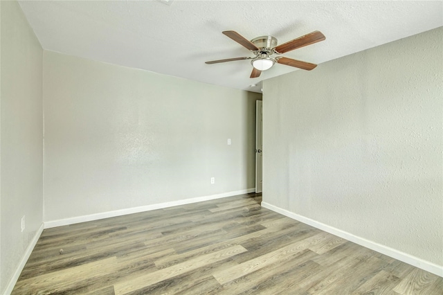 spare room featuring wood finished floors, a ceiling fan, and baseboards