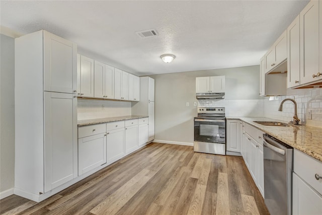 kitchen featuring stainless steel appliances, light wood-style floors, white cabinets, a sink, and under cabinet range hood