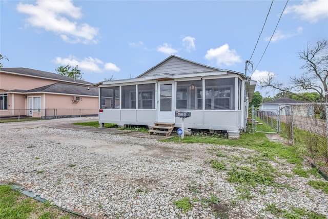 view of front of home featuring entry steps, fence, and a sunroom