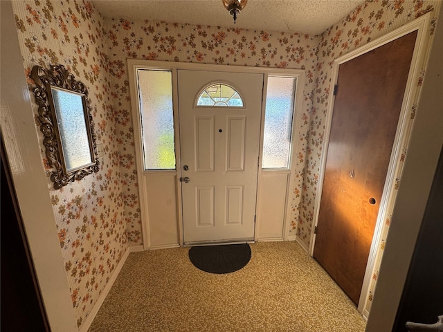 entryway with a healthy amount of sunlight, wallpapered walls, a textured ceiling, and light colored carpet