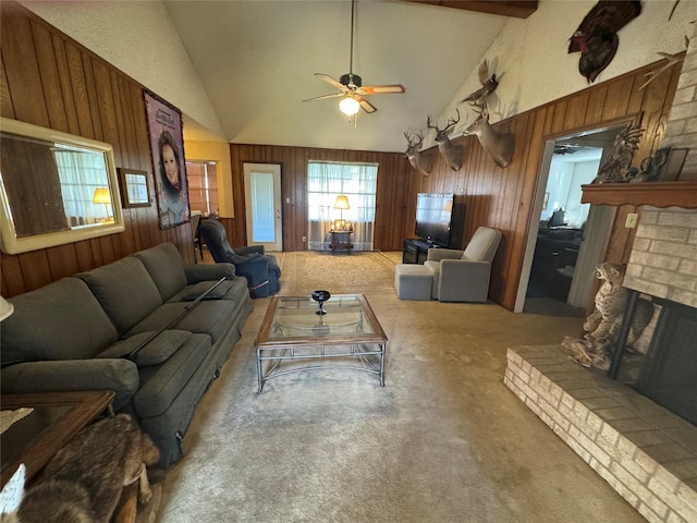 carpeted living area with ceiling fan, high vaulted ceiling, wood walls, a fireplace, and beamed ceiling