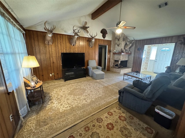 living room featuring lofted ceiling with beams, wood walls, a fireplace, and visible vents