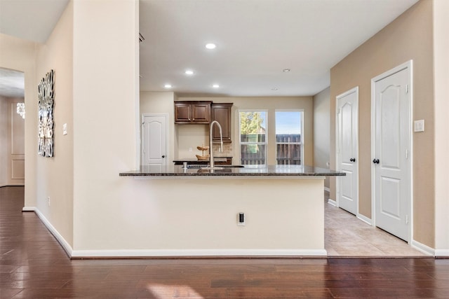 kitchen with light wood-style floors, baseboards, dark stone countertops, and recessed lighting