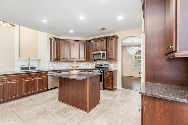 kitchen with arched walkways, visible vents, a center island, stainless steel appliances, and a sink