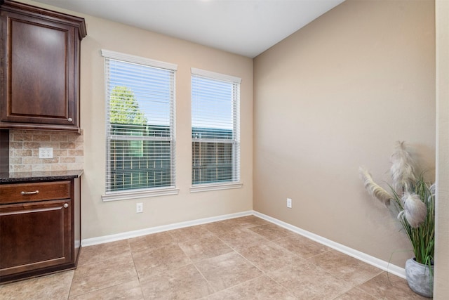 unfurnished dining area with light tile patterned flooring and baseboards