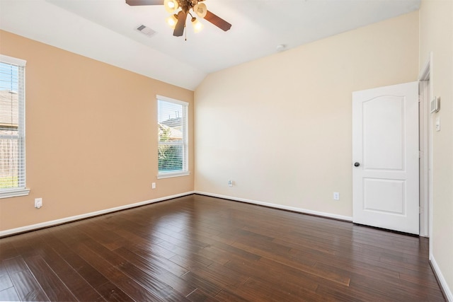 spare room featuring dark wood-style floors, lofted ceiling, visible vents, and baseboards