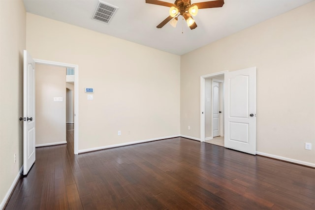 empty room with dark wood-type flooring, visible vents, ceiling fan, and baseboards