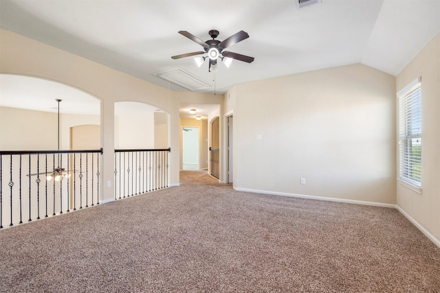 carpeted empty room with visible vents, attic access, a ceiling fan, vaulted ceiling, and baseboards