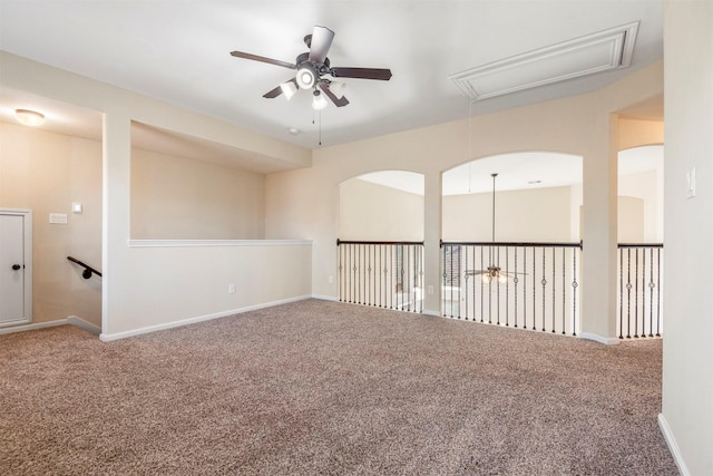 carpeted empty room featuring attic access, baseboards, and ceiling fan