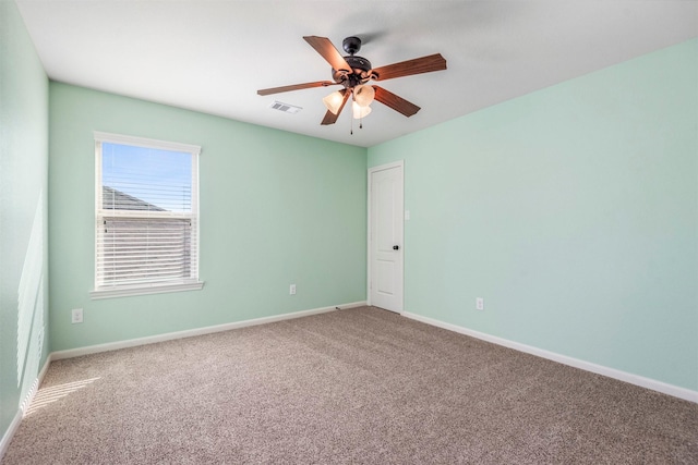 carpeted empty room featuring baseboards, visible vents, and ceiling fan