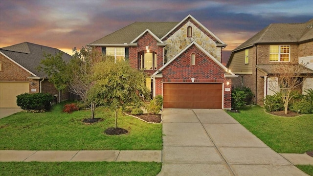 traditional home featuring a garage, driveway, stone siding, a yard, and brick siding