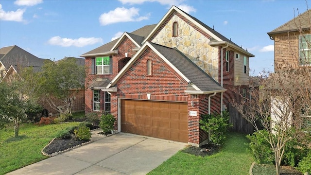 traditional-style home with driveway, stone siding, an attached garage, a front yard, and brick siding