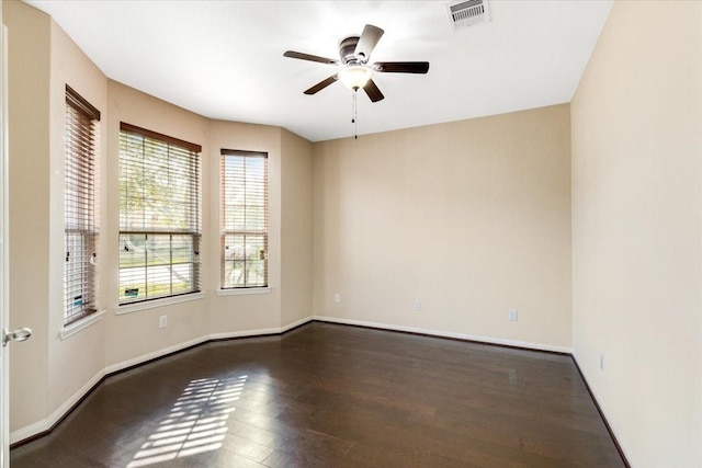 empty room with dark wood-style flooring, visible vents, ceiling fan, and baseboards