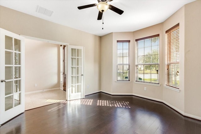 unfurnished room featuring french doors, dark wood finished floors, visible vents, ceiling fan, and baseboards