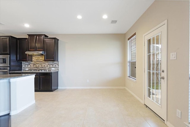 kitchen featuring dark brown cabinetry, visible vents, decorative backsplash, appliances with stainless steel finishes, and under cabinet range hood