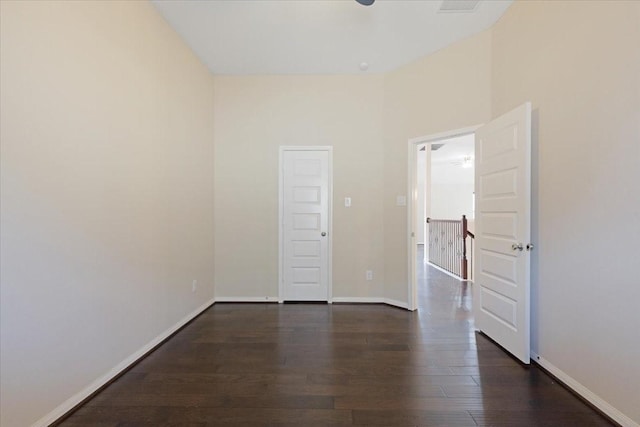 empty room featuring baseboards and dark wood-type flooring