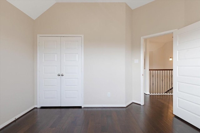 empty room with lofted ceiling, dark wood finished floors, and baseboards