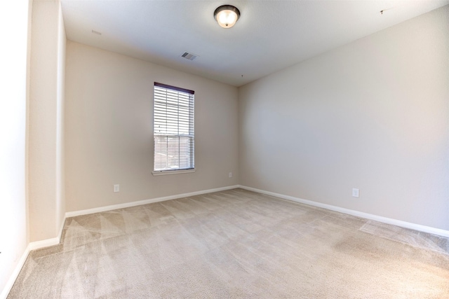 empty room featuring light colored carpet, visible vents, and baseboards