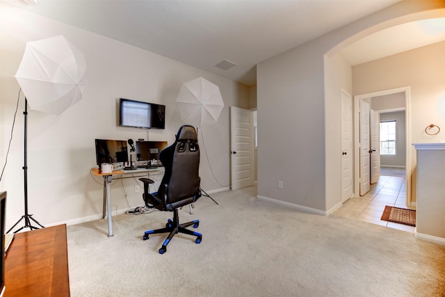 carpeted office space with arched walkways, visible vents, and baseboards