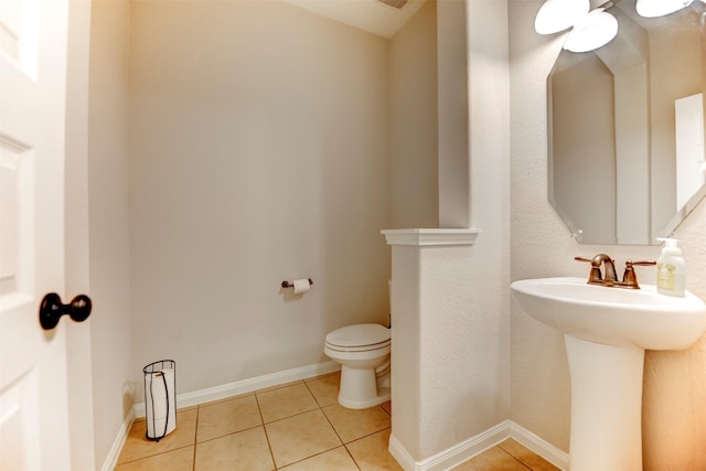 bathroom with a sink, tile patterned flooring, toilet, and baseboards