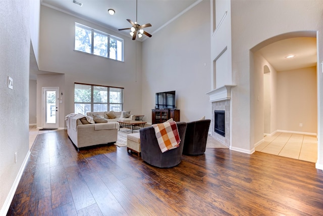 living area featuring a wealth of natural light, baseboards, a tiled fireplace, and wood finished floors