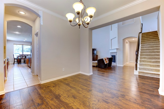 interior space featuring ornamental molding, wood finished floors, stairs, a fireplace, and a chandelier