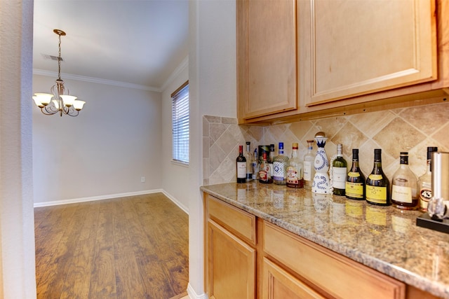 bar with a notable chandelier, tasteful backsplash, ornamental molding, wood finished floors, and baseboards