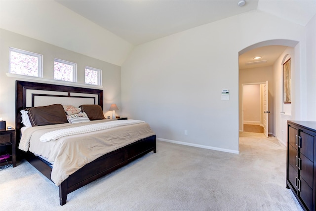 bedroom featuring light carpet, baseboards, vaulted ceiling, and arched walkways