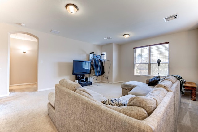 living area featuring baseboards, visible vents, arched walkways, and light colored carpet