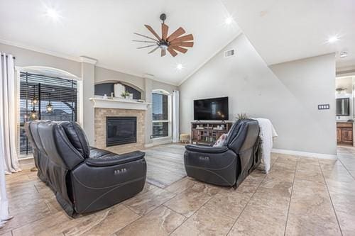 living area featuring lofted ceiling, ceiling fan, visible vents, baseboards, and a glass covered fireplace