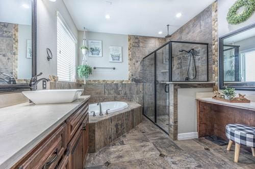 bathroom with a stall shower, a healthy amount of sunlight, a garden tub, and vanity