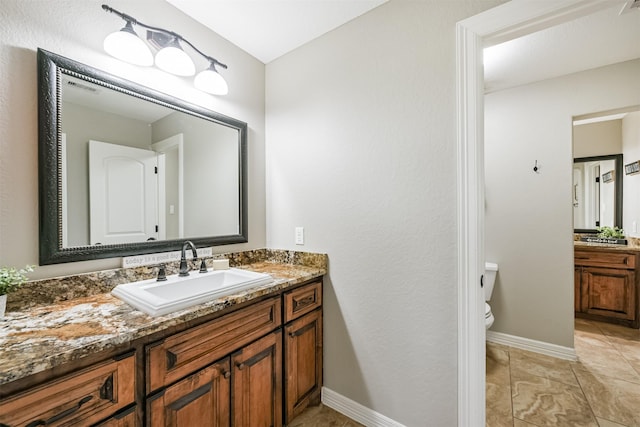 bathroom featuring baseboards, vanity, and toilet