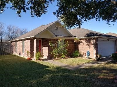 view of front of house with brick siding, an attached garage, and a front yard