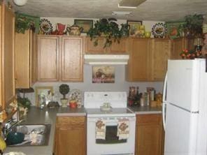 kitchen with white appliances, brown cabinetry, range hood, light countertops, and a sink