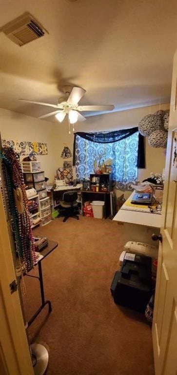 home office with carpet, visible vents, and a ceiling fan