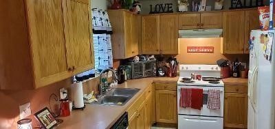 kitchen with light countertops, white appliances, a sink, and under cabinet range hood