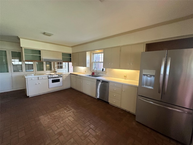 kitchen with light countertops, brick floor, appliances with stainless steel finishes, and a sink