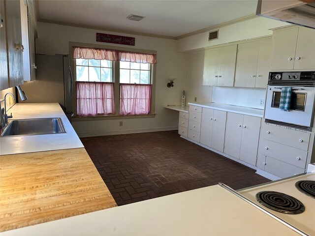 kitchen featuring a sink, crown molding, visible vents, and oven